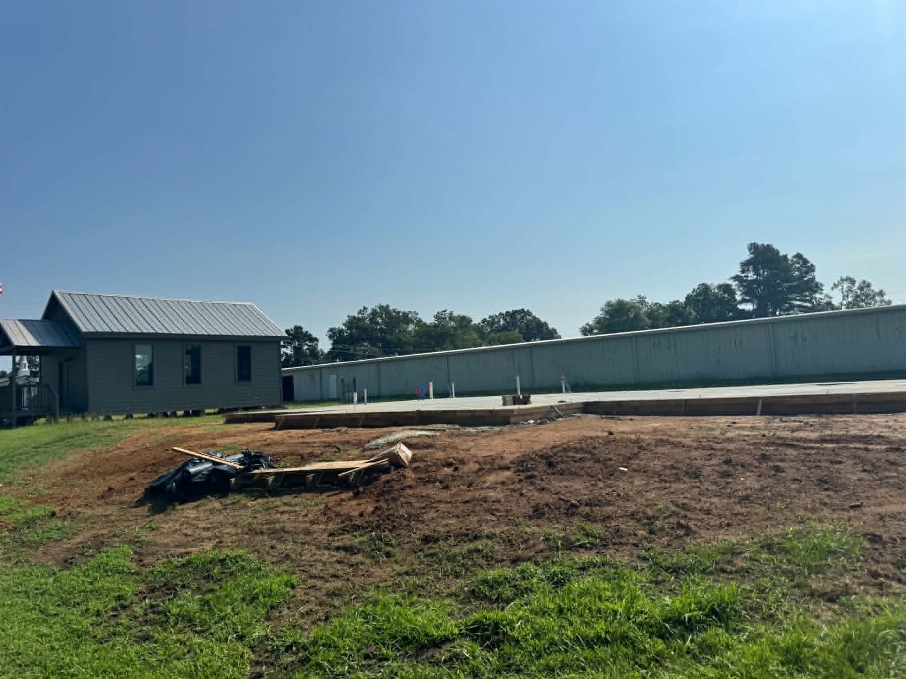 The poured concrete foundation slab for the Falkner Heritage Community Center, with the Cooper Hill School House standing to the left.