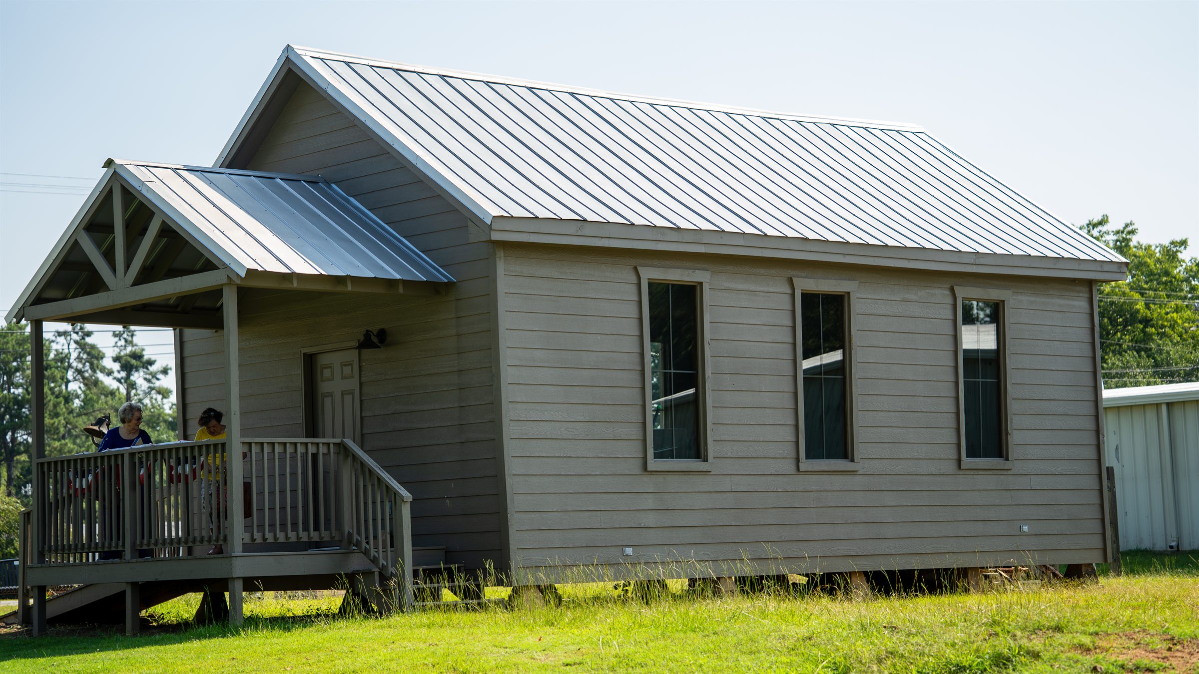 The restored Cooper Hill School House standing in Falkner Heritage Park under a clear blue sky.